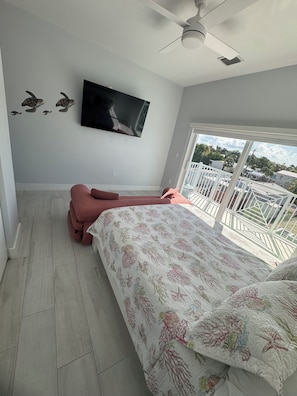 A bedroom with a bed, a television, and a balcony with a view. - Waterfront Lux Retreat/Pool, Dock, 4 Master Suites (Marathon)
