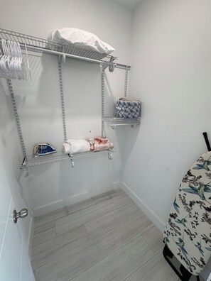 A laundry area with shelves, an ironing board, and a hanging rack. - Waterfront Lux Retreat/Pool, Dock, 4 Master Suites (Marathon)
