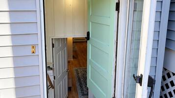 Un abri de jardin avec une porte ouverte, laissant entrevoir un intérieur doté d’un plancher en bois et d’un tapis.