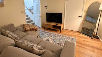 Un salon avec un canapé, un téléviseur, un tapis à motifs et un escalier.