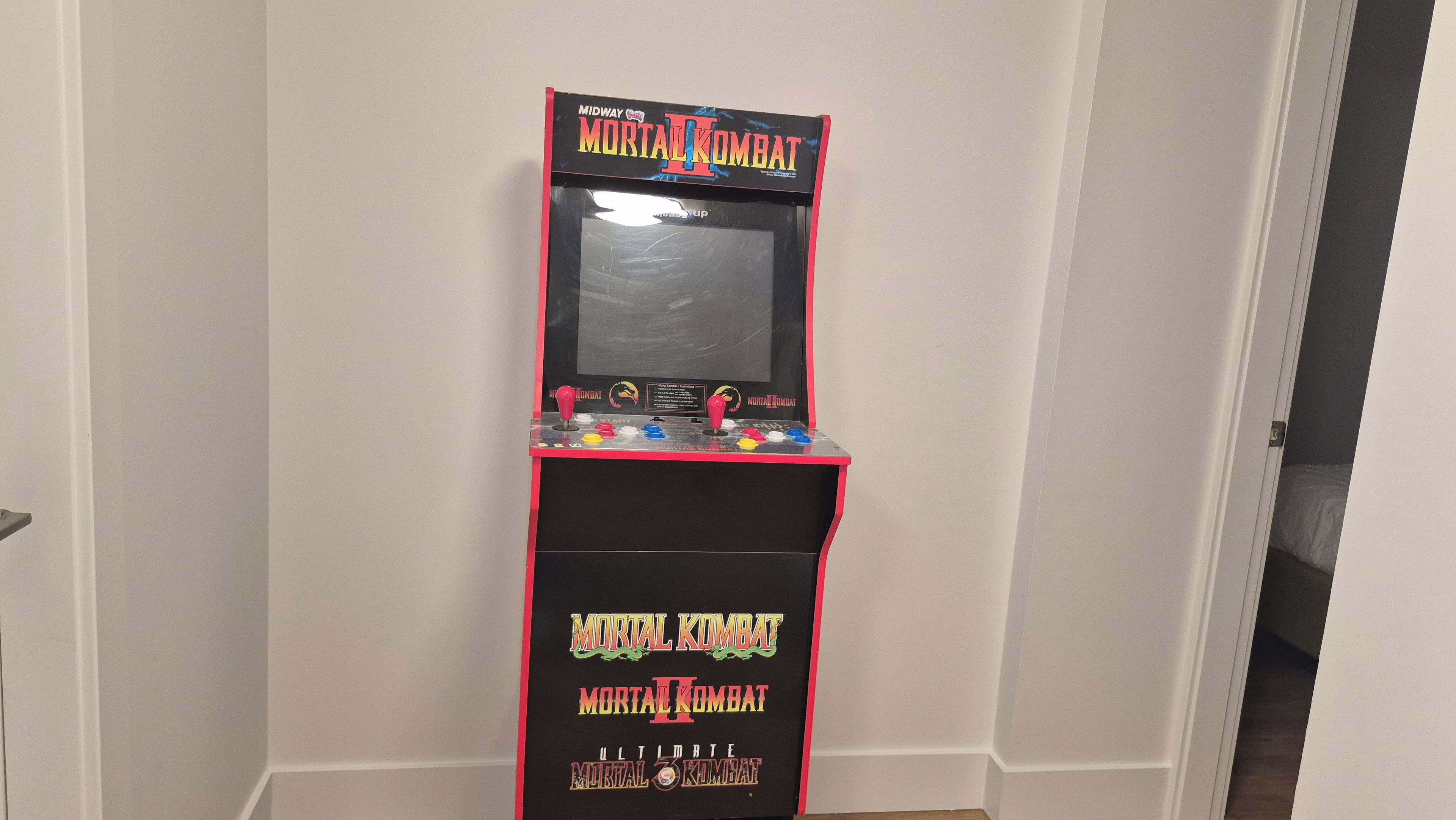 Une borne d’arcade rétro, avec le jeu Mortal Kombat II, dans un couloir.