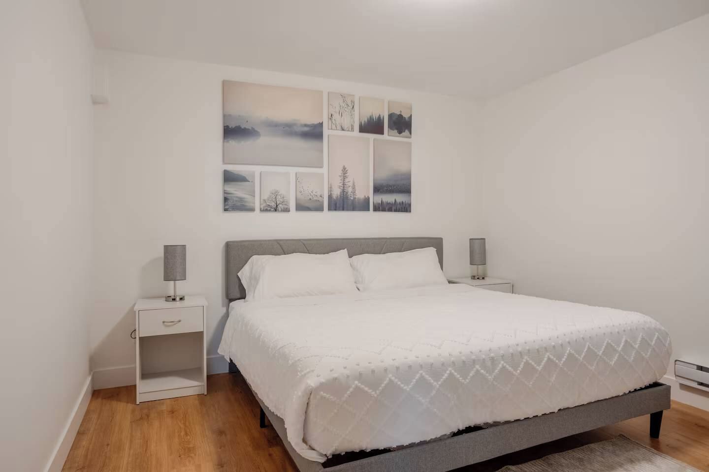 Une chambre à coucher avec un lit, deux tables de chevet et un mur orné de tableaux.