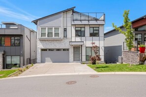 A modern two-story house with a garage, a small front yard, and a street view.