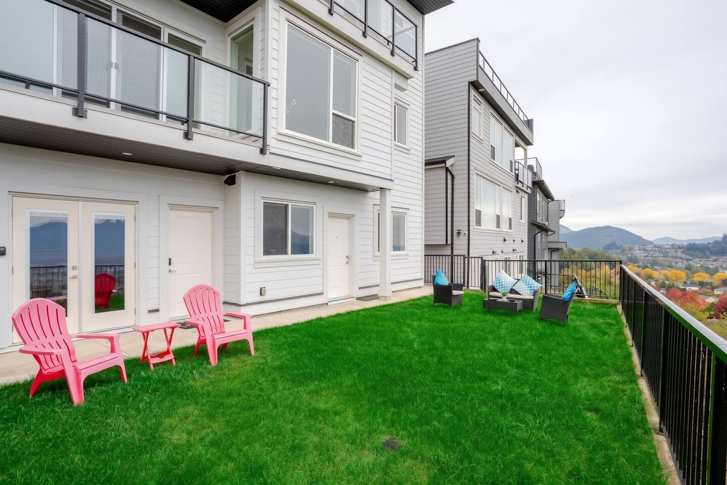 Un immeuble résidentiel doté d’un balcon, d’une cour verdoyante et d’un espace extérieur aménagé pour s’asseoir.