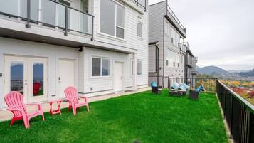 Un immeuble résidentiel doté d’un balcon, d’une cour verdoyante et d’un espace extérieur aménagé pour s’asseoir.
