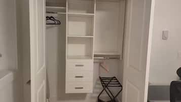 A walk-in closet with open doors, featuring multiple shelves, drawers, and a hanging rack.