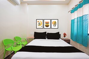 A hotel room with a bed, two chairs, a nightstand, and three framed pictures on the wall. - Collection O Thanisandra Bangalore Surya (Bengaluru)