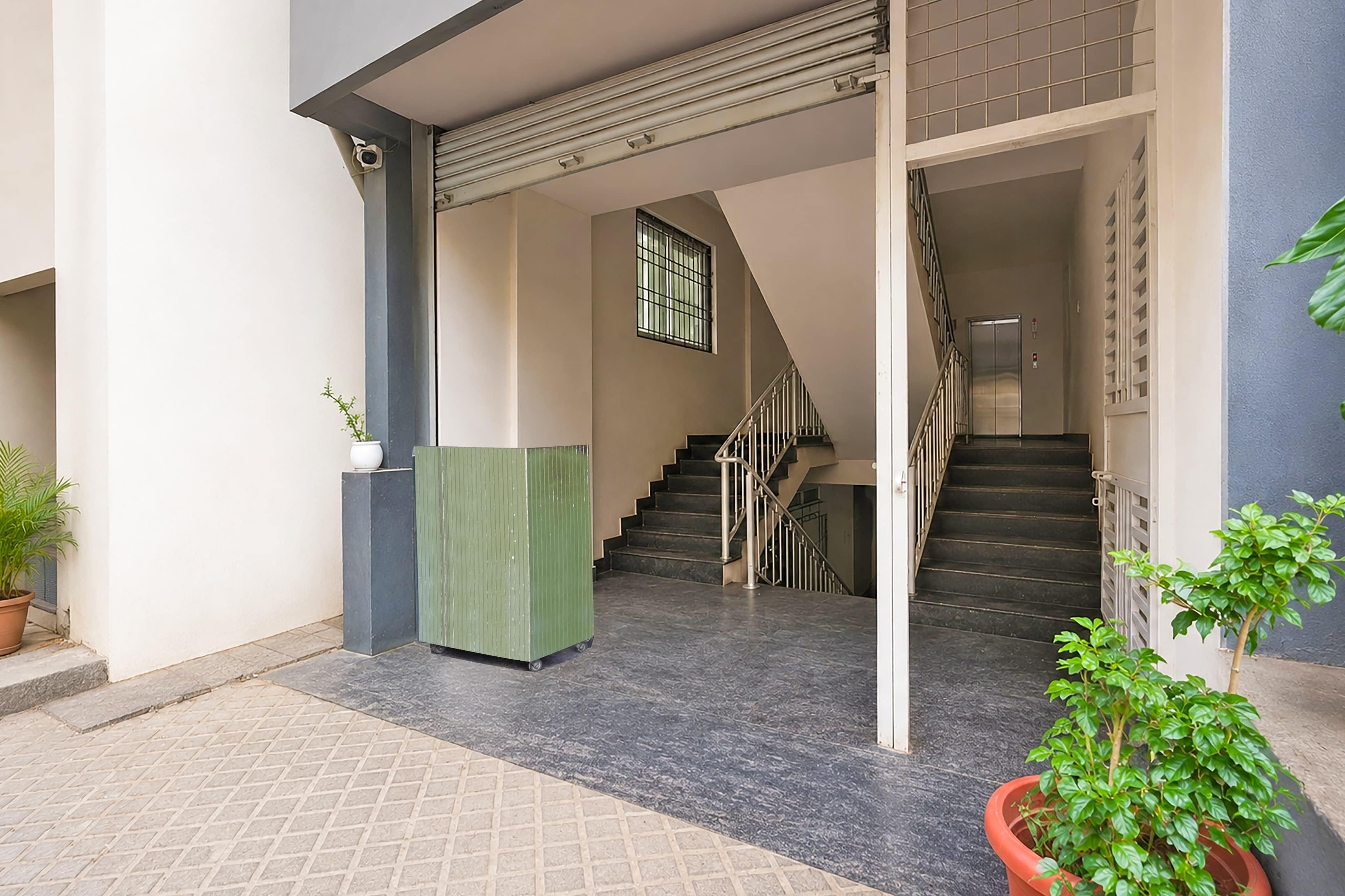 L’entrée d’un immeuble, avec un escalier menant à un étage supérieur, une caméra de surveillance et des plantes en pot.