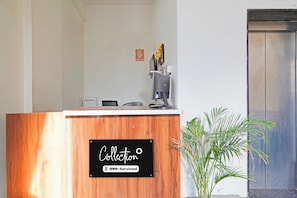 A reception desk with a wooden finish and a sign that reads 'Collection OYO-Serviced'. - Collection O Thanisandra Bangalore Surya (Bengaluru)