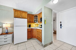Eine kleine Küche mit Holdekor-Schränken, einem weißen Kühlschrank und einer Spüle.