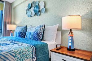 A hotel room with a bed, a nightstand with a lamp, and decorative wall art.