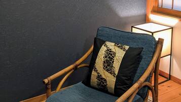 A room with a wooden rocking chair, a framed picture of a car, and a framed Tokyo 1964 poster.
