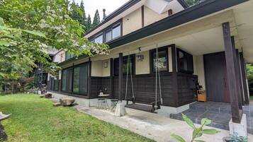 A modern house with a covered porch, large windows, and a garden area with a swing set.