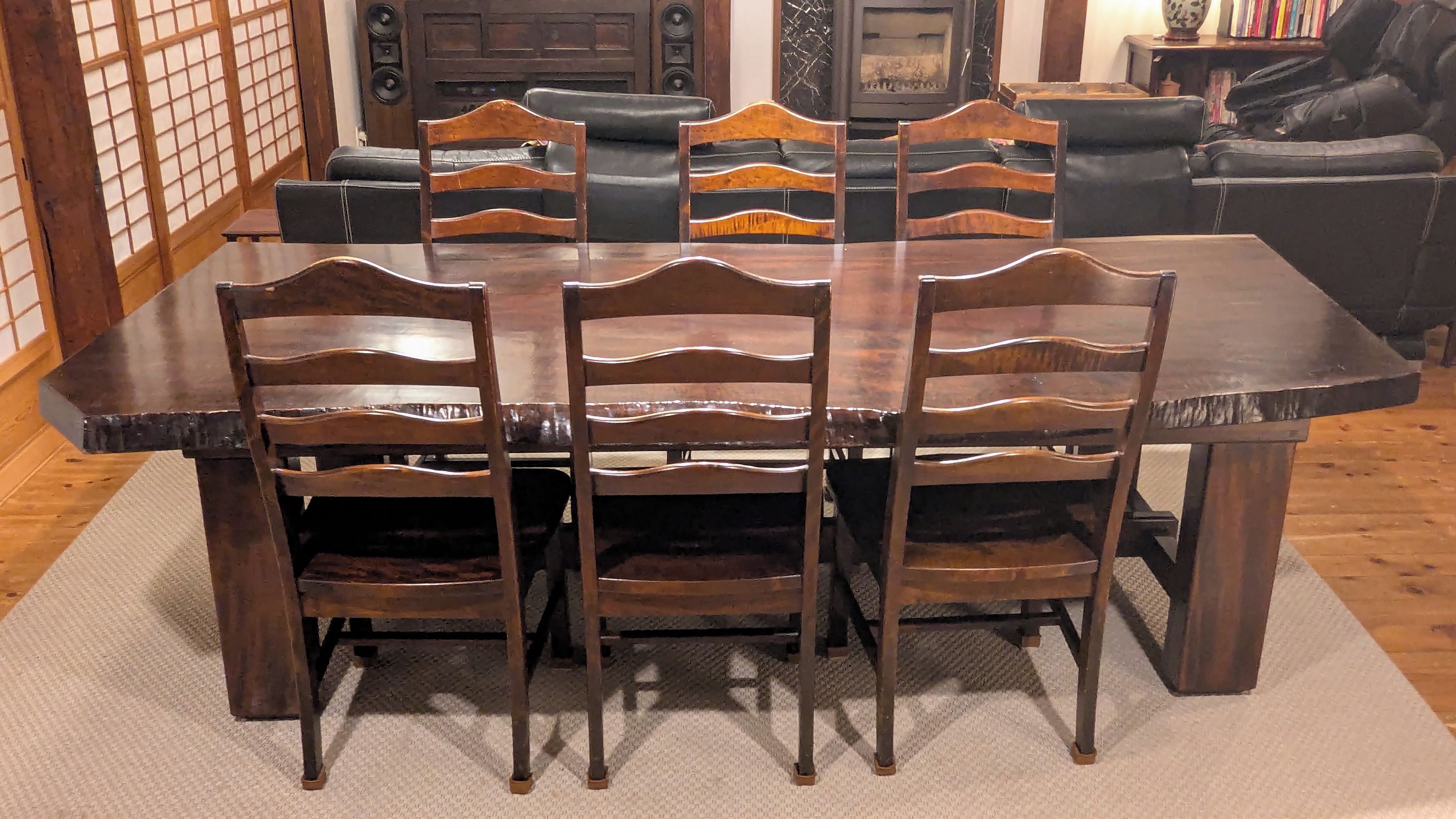 Un comedor con una mesa y sillas de madera, una chimenea y una estantería al fondo.