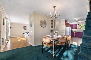 A spacious living area with a dining table, chairs, a chandelier, and a view of the kitchen. - Grand Lake Sunset Haven Relax Unwind Stay (Oakfield)