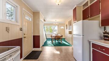 A kitchen with a dining area, a refrigerator, and a window.