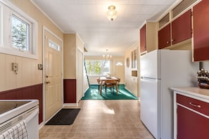 A kitchen with a dining area, a refrigerator, and a window. - Grand Lake Sunset Haven Relax Unwind Stay (Oakfield)