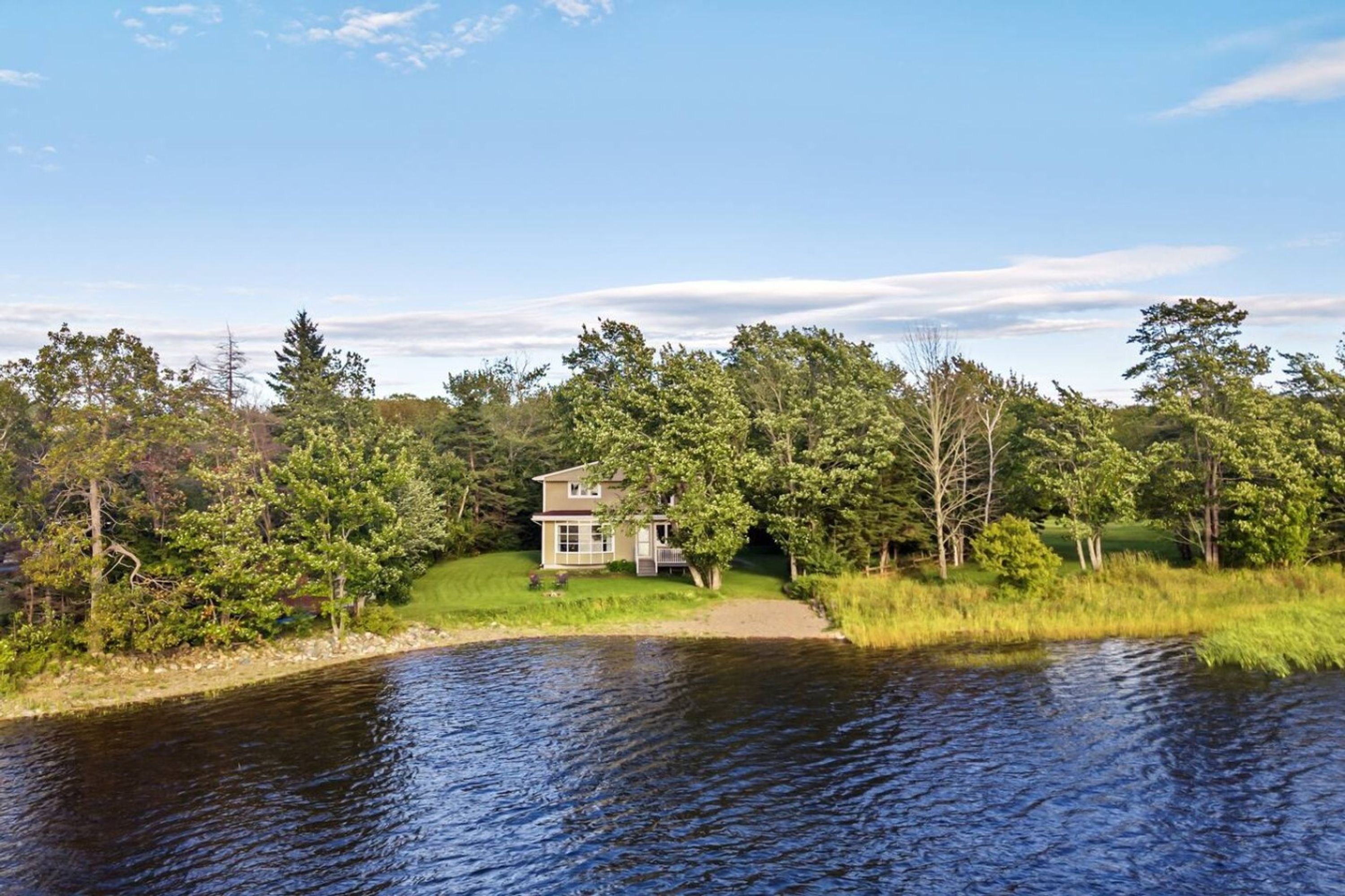 A house by a lake surrounded by trees.