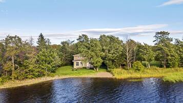 A house by a lake surrounded by trees.