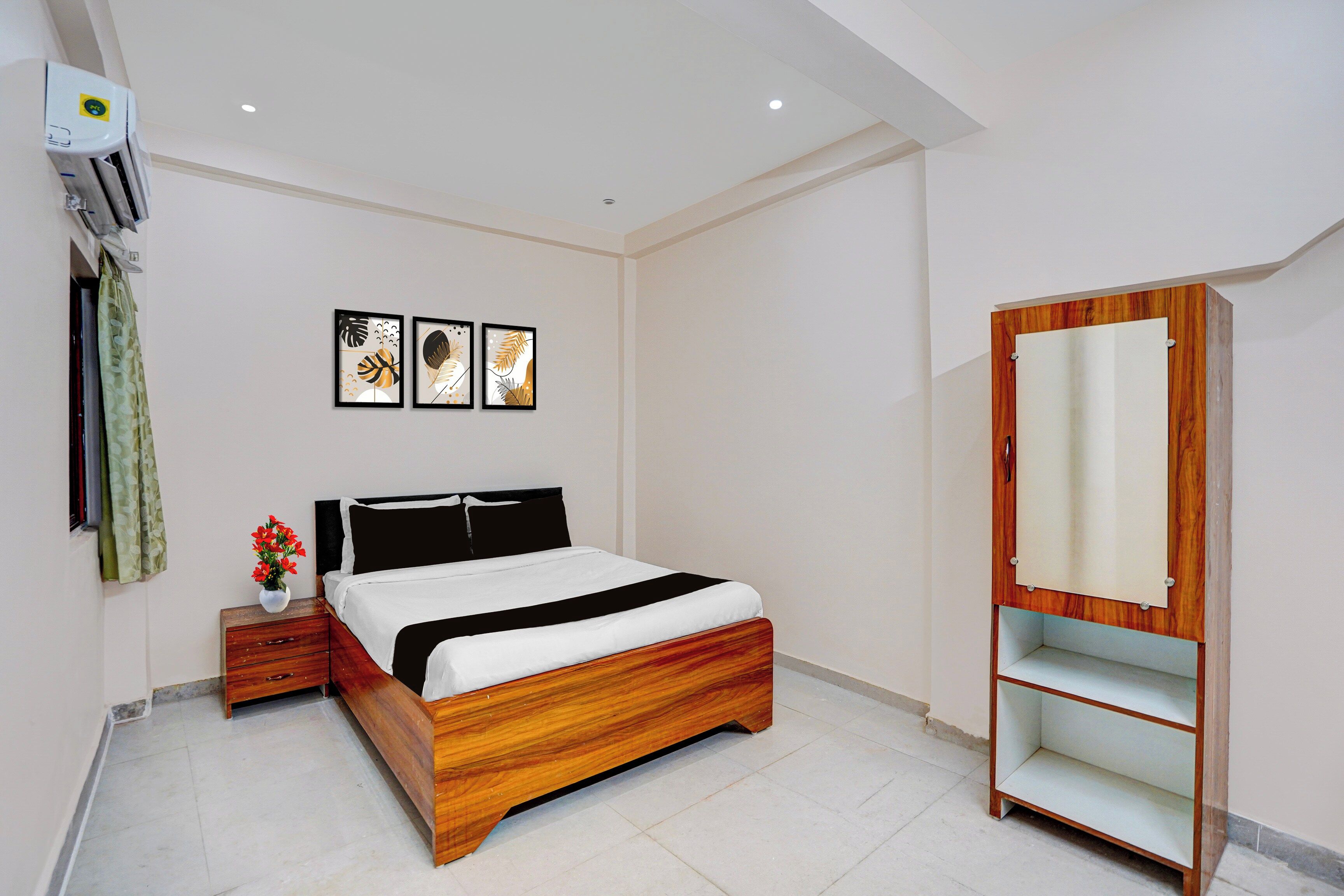 Een slaapkamer met een houten bed, nachtkastje, een wandairconditioner en een houten garderobe met spiegel.