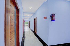 A hotel corridor with wooden doors, a fire extinguisher mounted on the wall, and a fire exit sign.