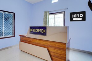 A reception desk with a sign indicating a hotel service, a window with a view, and a wall-mounted sign for the hotel.