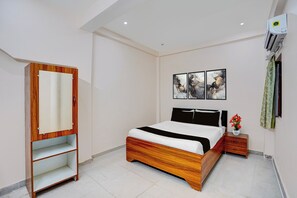 A bedroom with a bed, a wardrobe, a nightstand, and wall art.