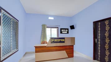 A reception desk with a sign indicating a reception area, a window with curtains, and a door with decorative paneling.