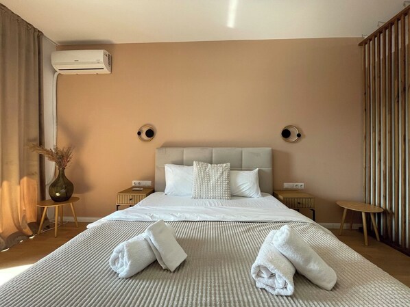 A hotel room with a bed, two bedside tables, an air conditioning unit, and a window with curtains. - Golden Berryl w AC and Smart TV (Brașov)
