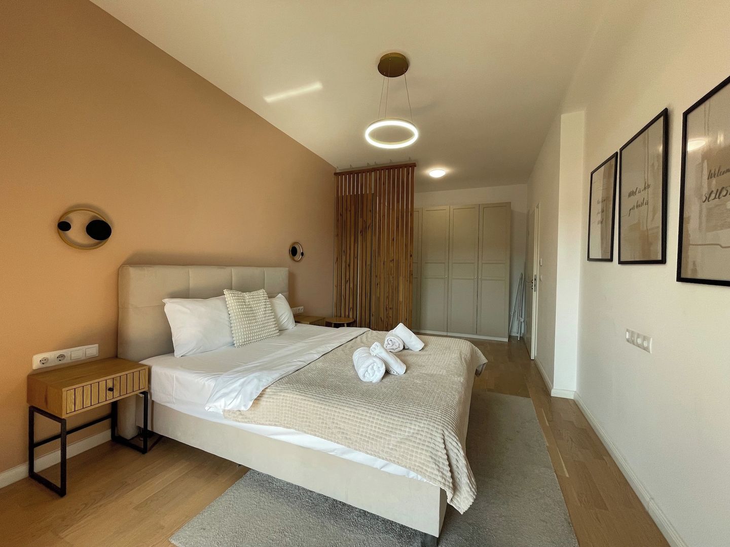 A modern bedroom with a large bed, bedside tables, a wardrobe, and a ceiling light fixture.