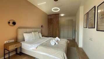 A modern bedroom with a large bed, bedside tables, a wardrobe, and a ceiling light fixture.