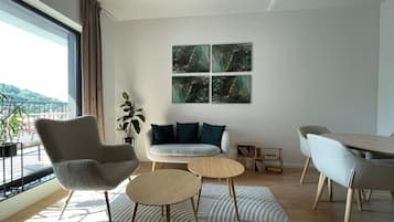 A modern living room with a sofa, two round tables, a chair, and a bookshelf.