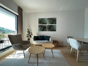 A modern living room with a sofa, two round tables, a chair, and a bookshelf. - Golden Berryl w AC and Smart TV (Brașov)