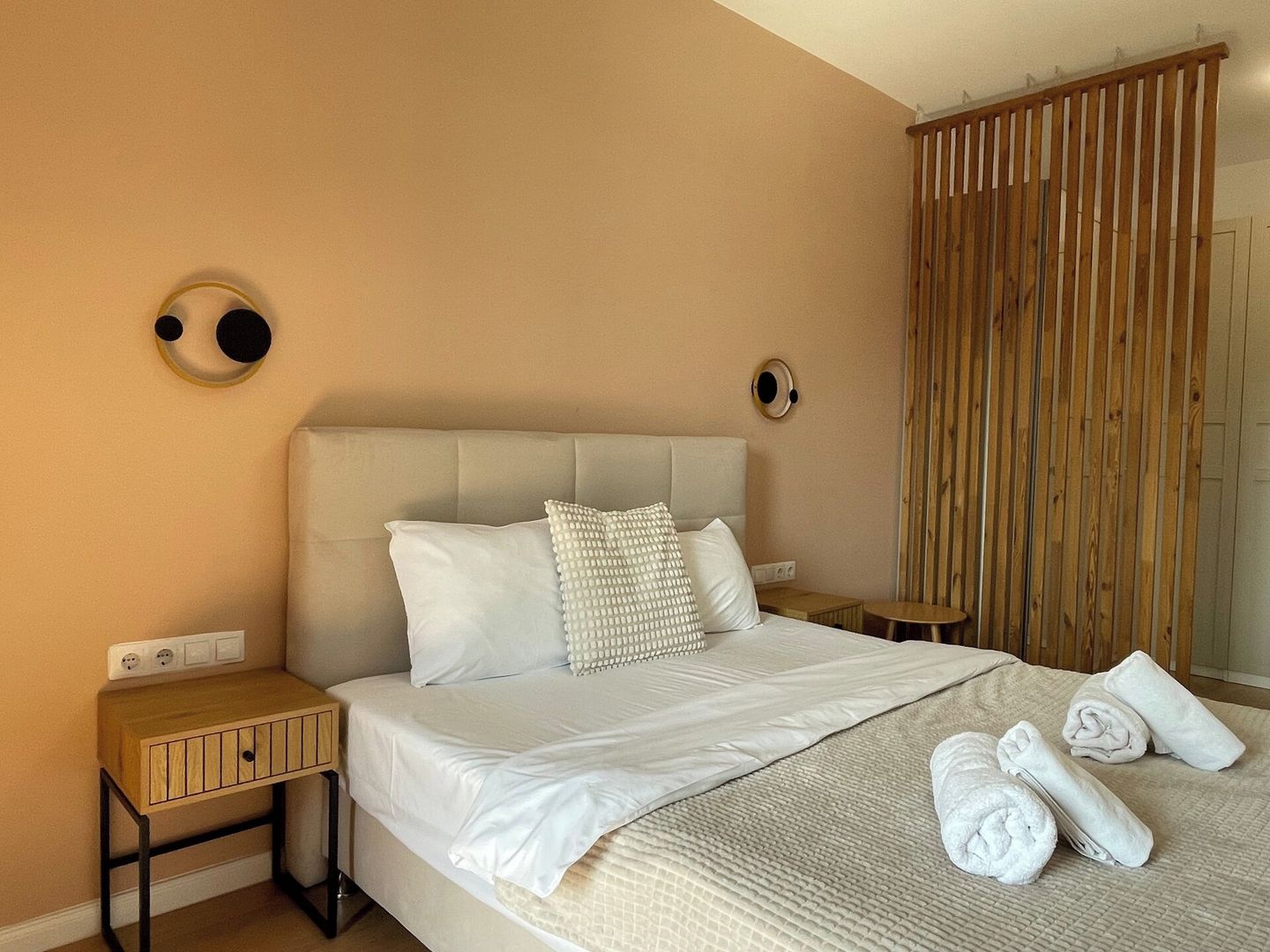 Een hotelkamer met een bed, nachtkastjes en een houten scheidingswand.