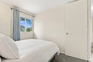 Une chambre à coucher avec un lit, une fenêtre avec des rideaux et une porte.