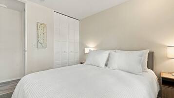 A bedroom with a large bed, a wardrobe, and a wall-mounted artwork.