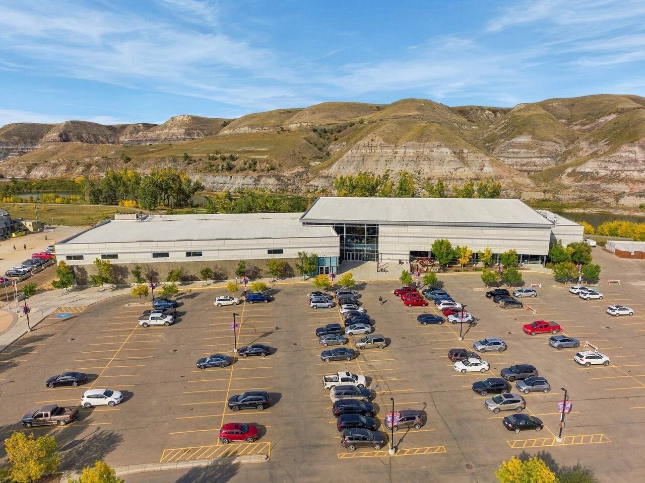 A large parking lot with multiple cars and a building with a flat roof in the background.
