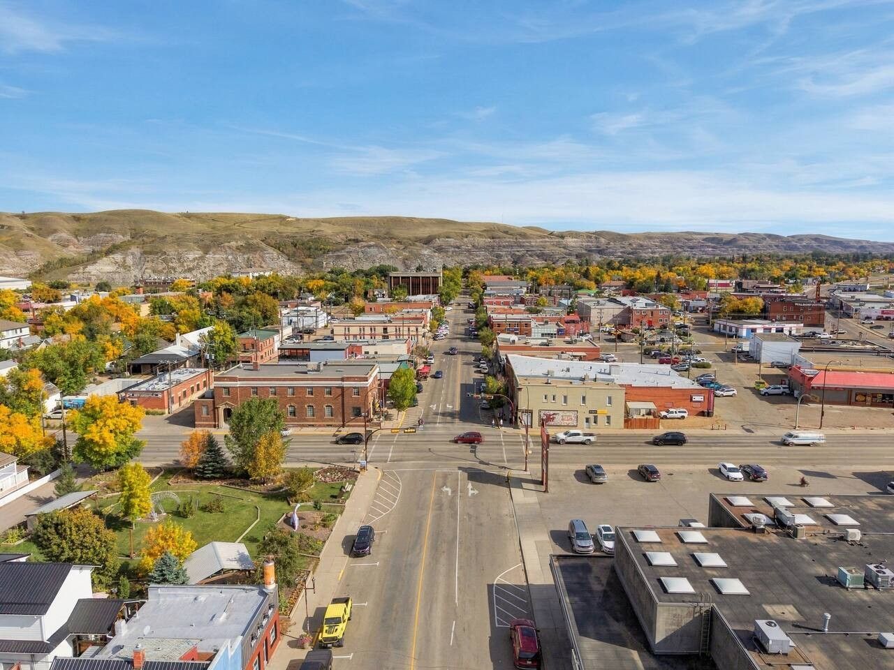 Une ville avec une rue principale, des bâtiments et un parking.