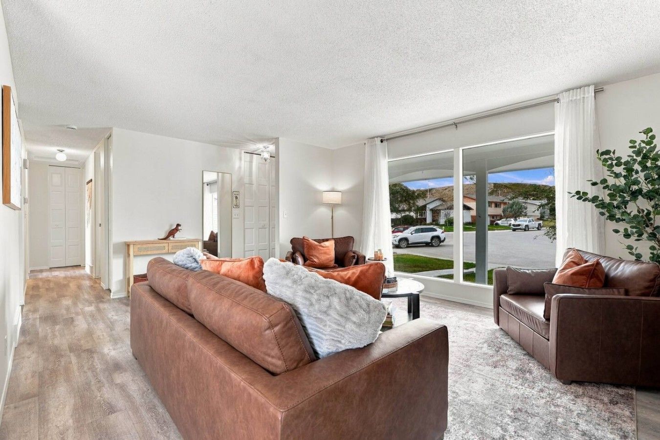 A spacious living room with a large window, a fireplace, and a view of the street.
