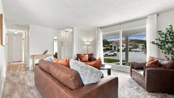 A spacious living room with a large window, a fireplace, and a view of the street.