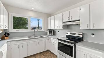 A modern kitchen with white cabinets, a built-in oven, and a window providing a view of the outdoors.