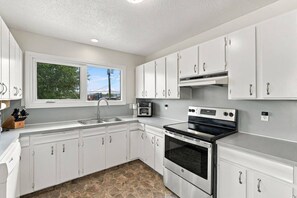 A modern kitchen with white cabinets, a built-in oven, and a window providing a view of the outdoors.