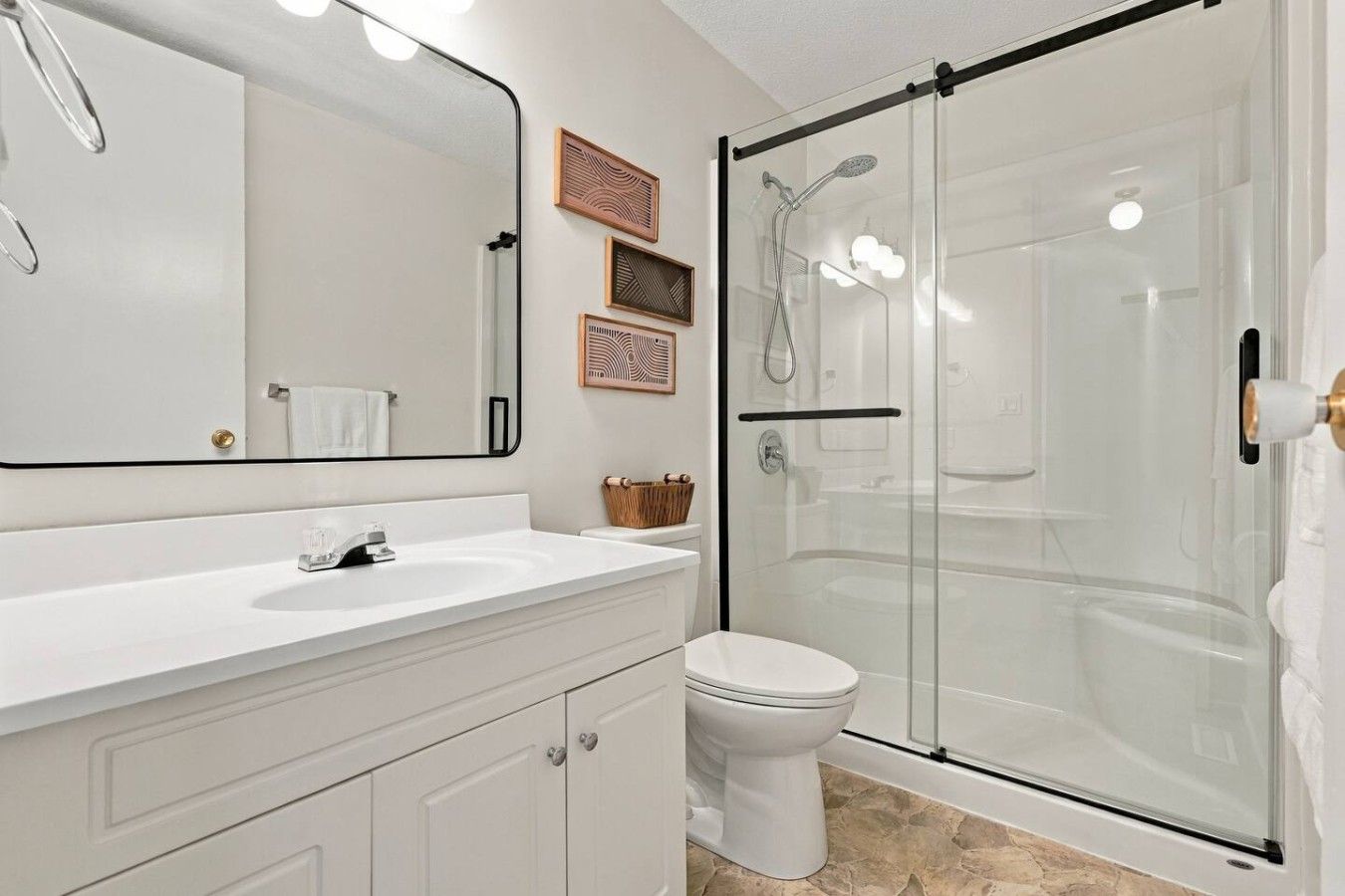 A bathroom with a white sink, a toilet, and a glass-enclosed shower.