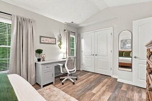 Ein Schlafzimmer mit Schreibtisch, Stuhl, Bett und Kleiderschrank.