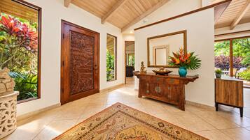 A spacious hallway with a wooden door, a large mirror, and a decorative cabinet.