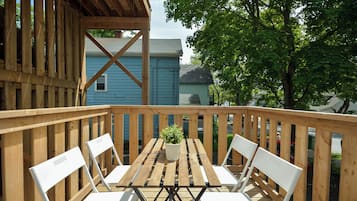 A wooden deck with a table and chairs, overlooking a residential area with houses and trees.