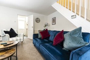 A living room with a blue sofa, striped armchair, and a coffee table. - The Cosy Pavilion Stylish 2BR Home With Free Street Parking (Durham)