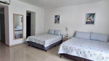 Een kamer met twee bedden, een spiegel en twee aan de muur hangende foto's.