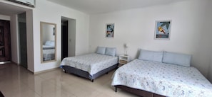 Habitació amb dos llits, un mirall i dues làmines penjades a la paret.