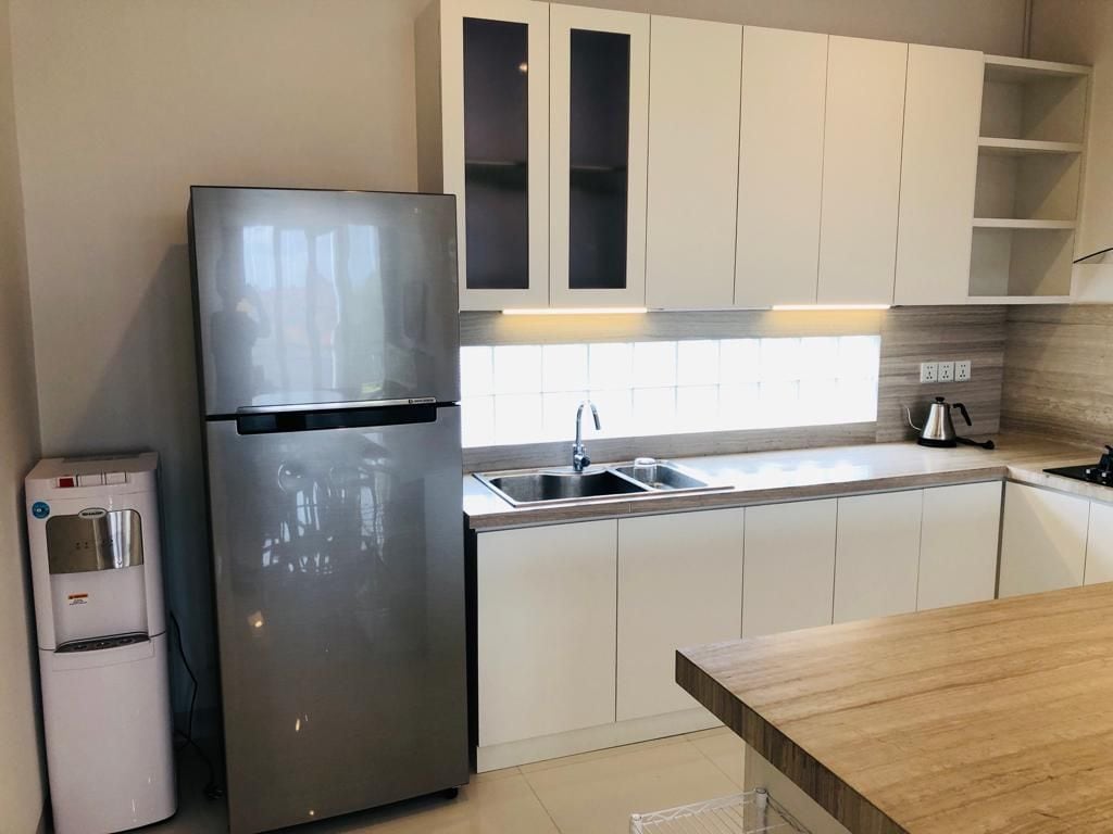 A modern kitchen with a stainless steel refrigerator, a water dispenser, a sink, and wooden countertops.